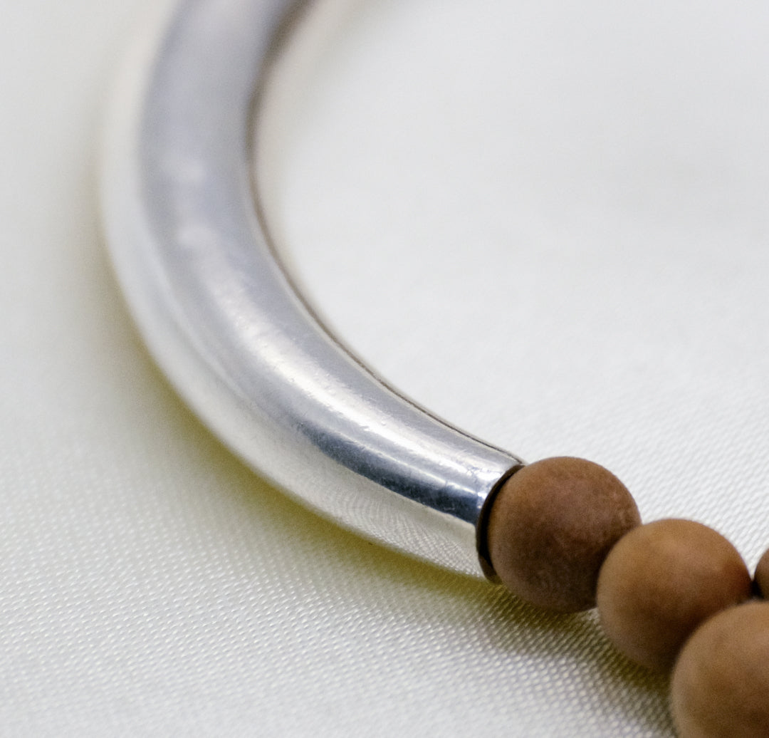Solid 925 sterling silver crescent tube featured on a natural sandalwood mindfulness bracelet