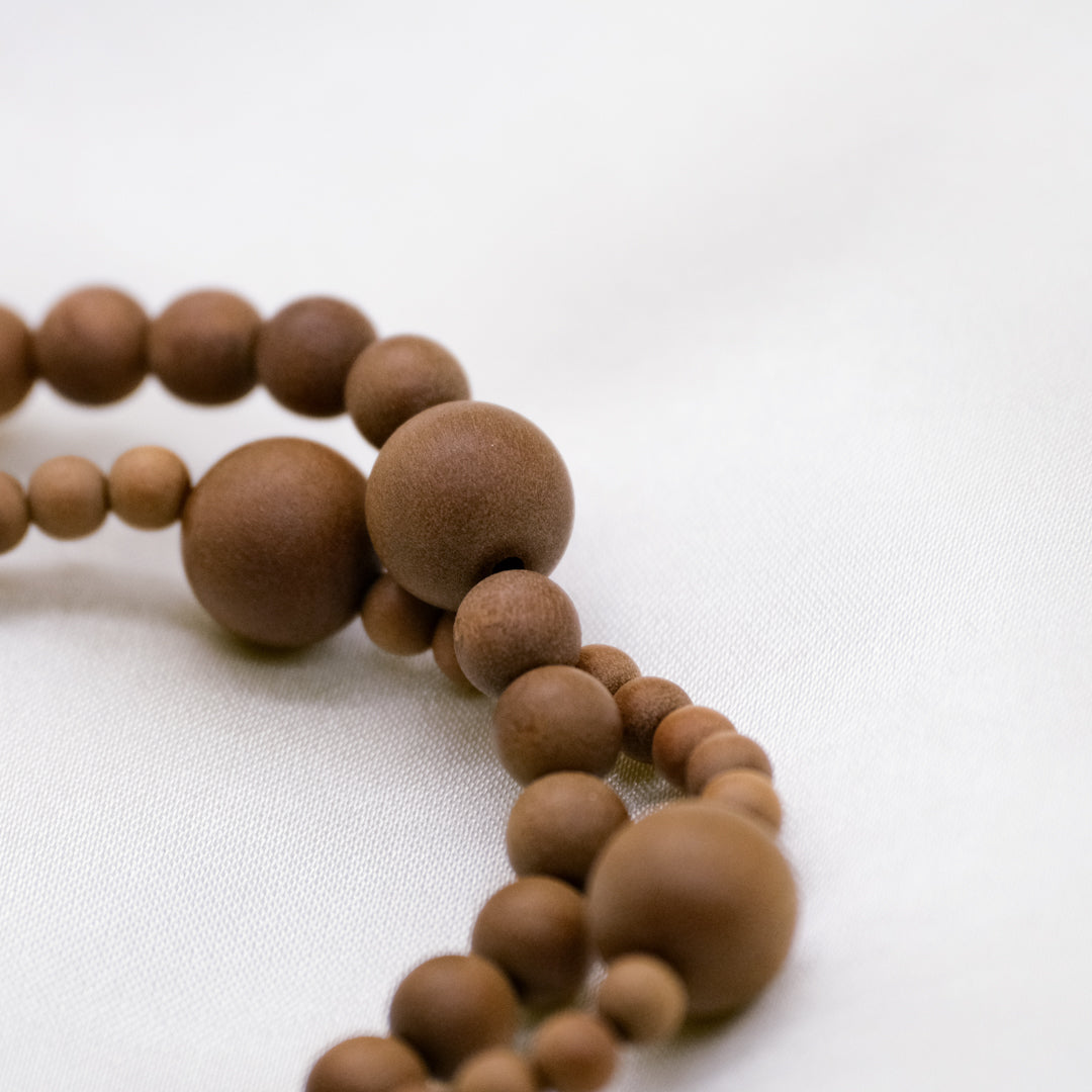 Macro detail of authentic aged Australian sandalwood beads showing natural wood grain and creamy texture.